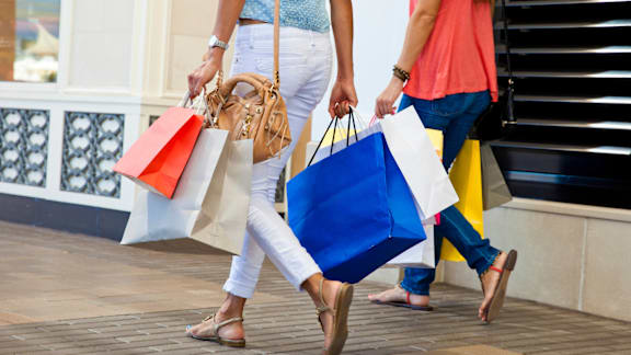 Two people walking with shopping bags.