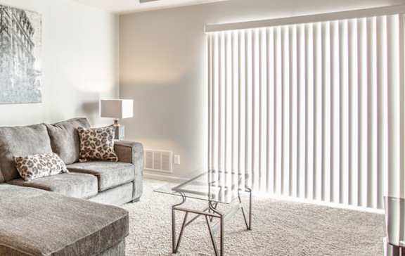 A living room with a grey couch, a coffee table, and a lamp.