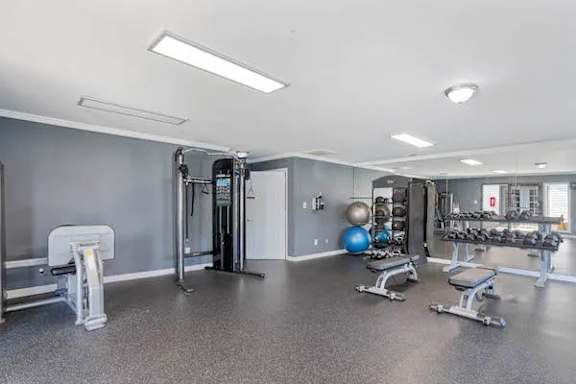 A spacious gym with a variety of equipment including a treadmill, weights, and a bench press at The Onyx Hoover Apartments, Alabama, 35216