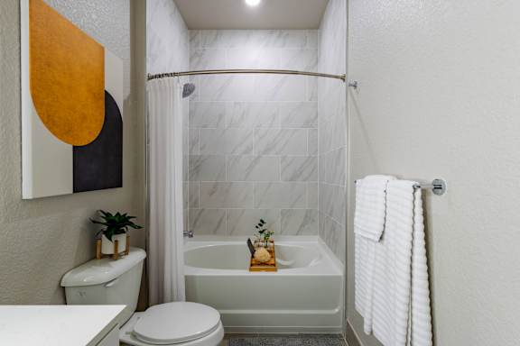 A bathroom with a white toilet, a white bathtub, and a white shower curtain.at Icon One, Florida, 32114