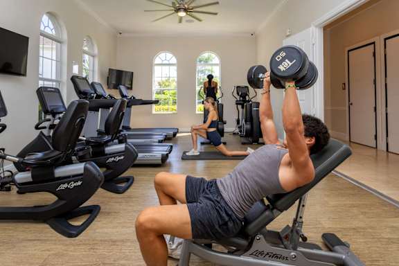 Man lifting weights in gym at The Falls of Portofino , Naples, 34119