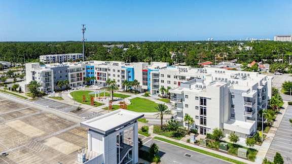 A modern building complex with a parking lot in front.at Icon One, Florida, 32114