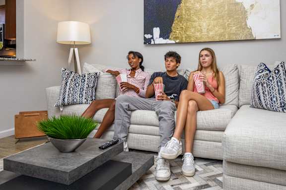 Three people are sitting on a couch with popcorn and watching television at Portofino Cove, Fort Myers, FL
