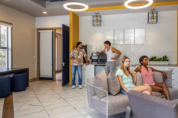 Four people are sitting on a couch in a modern living room at Portofino Cove, Fort Myers, FL, 33916