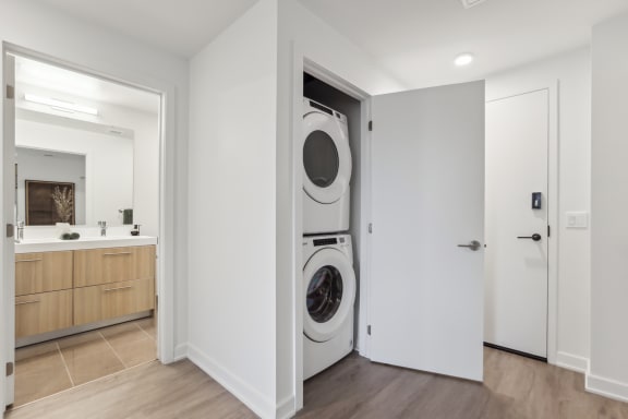 a front loader washer and dryer in a white room with a door open