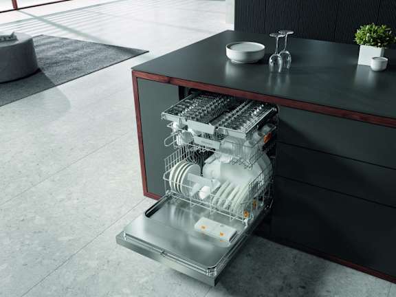 an open dishwasher in a kitchen next to a black table