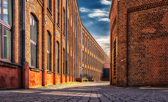 exterior shot of two brick factory buildings with brick walkway between