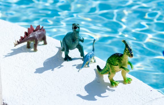 a group of toy dinosaurs on a table next to a pool