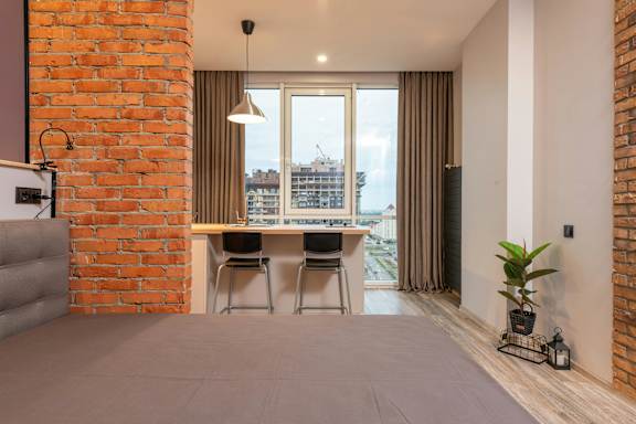 A room with a brick wall and a grey carpet.