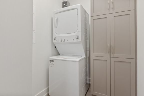 a washer and dryer in a laundry room with white cabinets