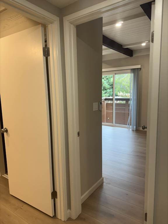 A white door is open to a room with wooden floors.