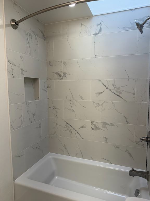 A white bathtub in a bathroom with marble tiles.