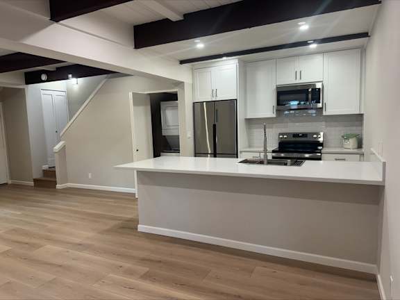 A kitchen with white cabinets and a wooden floor.