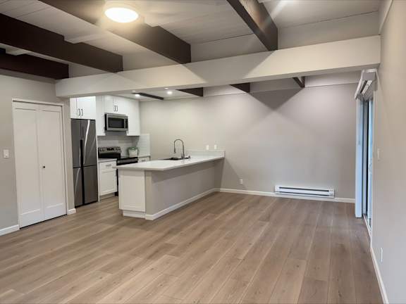 A kitchen with a refrigerator, microwave, and sink.