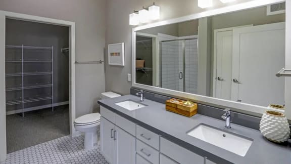 a bathroom with two sinks and a toilet and a large mirror