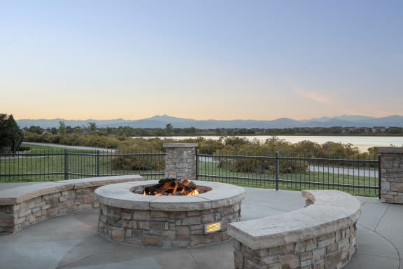 a fire pit and seating area on a patio with a view of a lake and mountains