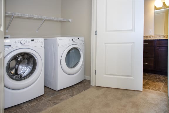 Front loading washer and dryer stored in a spacious in-unit closet with plenty of storage above on a shelf.