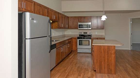 A kitchen with wooden cabinets and a stainless steel refrigerator.