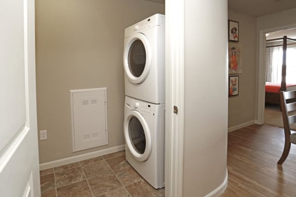 In unit washer and dryer stacked on top of eachother in small room off of kitchen