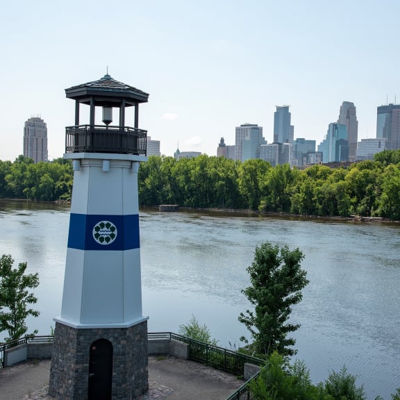 the lighthouse at the river with the city skyline in the background
