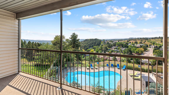 a balcony with a view of a swimming pool and trees