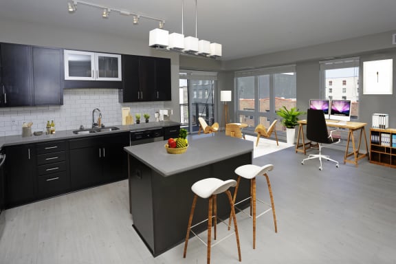 Kitchen with island and barstools, overhead lights and stainless steel appliances