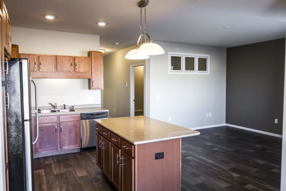 Kitchen with an island as the focal point with pendant lighting. Kitchen area opens up to the living area and natural light fills the space.