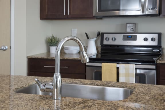 Close up on stainless steel sink on granite countertop of kitchen island