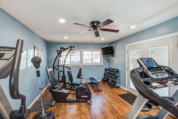 A home gym with a treadmill, elliptical trainer, and other exercise equipment.