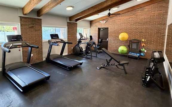 A home gym with treadmills, elliptical machines, and other exercise equipment.