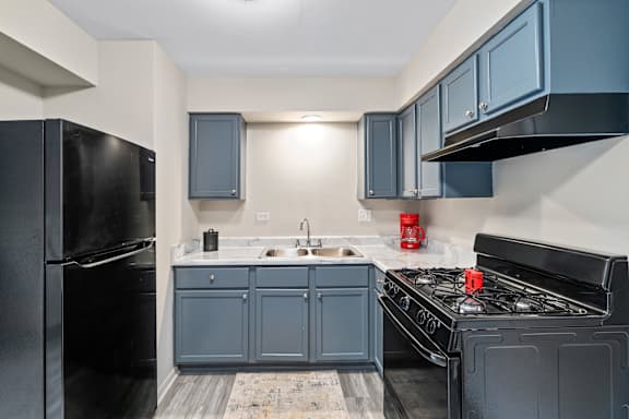 a kitchen with blue cabinets and a black stove and refrigerator at Hanover Park Blu Apartments, Hanover Park