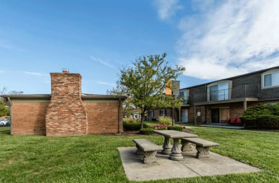 a picnic table sits in the grass in front of a brick building