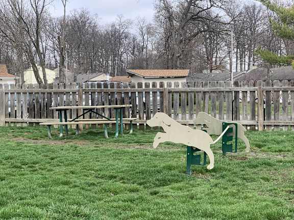 a park with a rocking horse and picnic tables