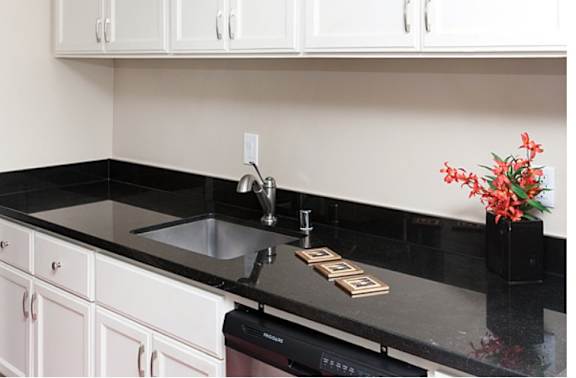 A kitchen with black countertops and white cabinets.