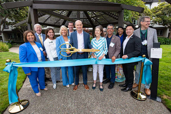 A group of people are gathered around a ribbon cutting ceremony.