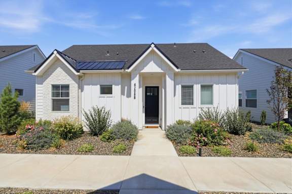 A white house with a black roof and a grey front door.