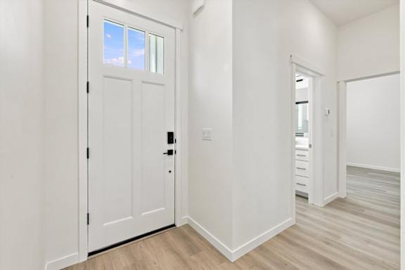 A white door with a black handle is in a room with white walls and wooden flooring.