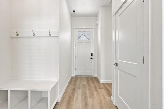 A white hallway with a bench and coat hooks.