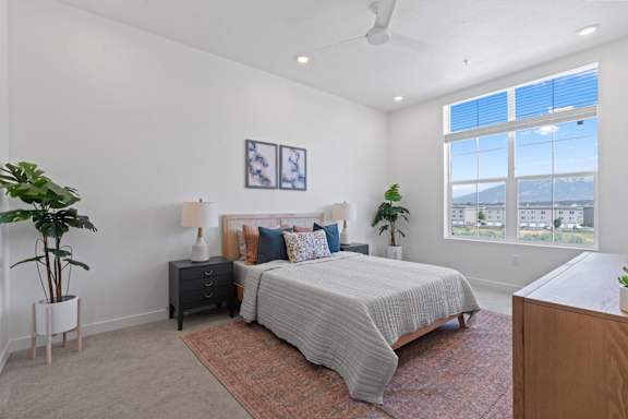 A bedroom with a large bed, a nightstand, and a window overlooking the city.