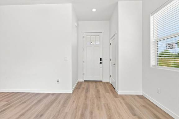 A white hallway with wood flooring and a white door.