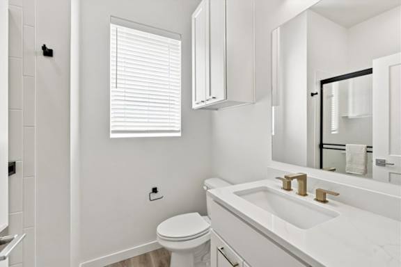 A white bathroom with a toilet, sink, and mirror.