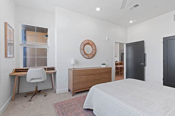 A bedroom with a bed, desk, and chair.