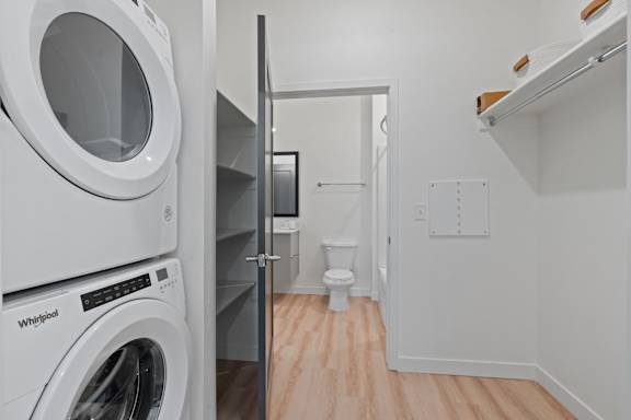 A white Whirlpool washing machine sits next to a white toilet in a small laundry room.