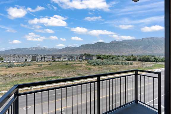 A balcony overlooks a road with a mountain range in the distance.