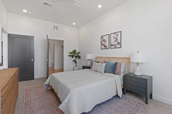 A bedroom with a bed, nightstand, and two doors.