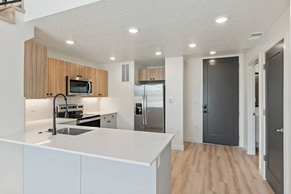 A modern kitchen with a white countertop and wooden cabinets.