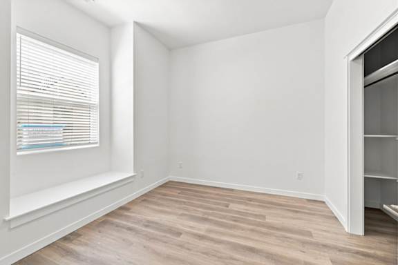 A room with a window and wooden flooring.