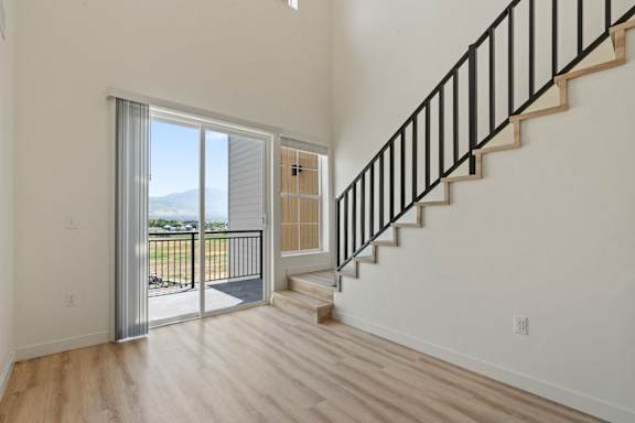 A staircase with a black railing leads to a balcony with a glass door.
