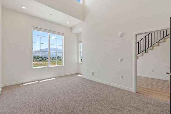 A large, empty room with a staircase and a window overlooking a landscape.
