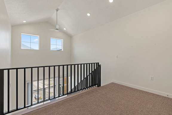 A room with a carpeted floor and a black railing.
